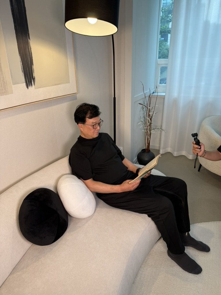 A man wearing the CuraOnes adaptive jumpsuit, reading in a living room